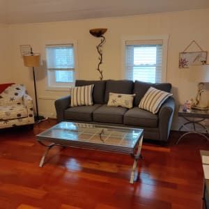 A living room with a couch , chair , coffee table and lamp.