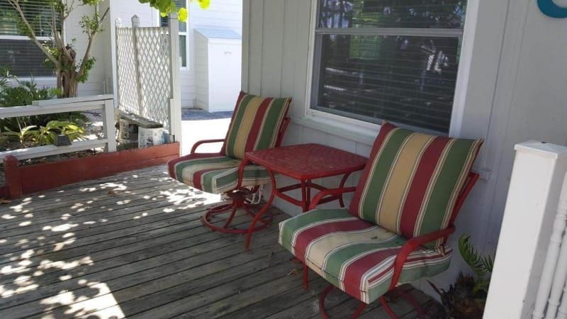 A porch with two chairs and a table in front of a window