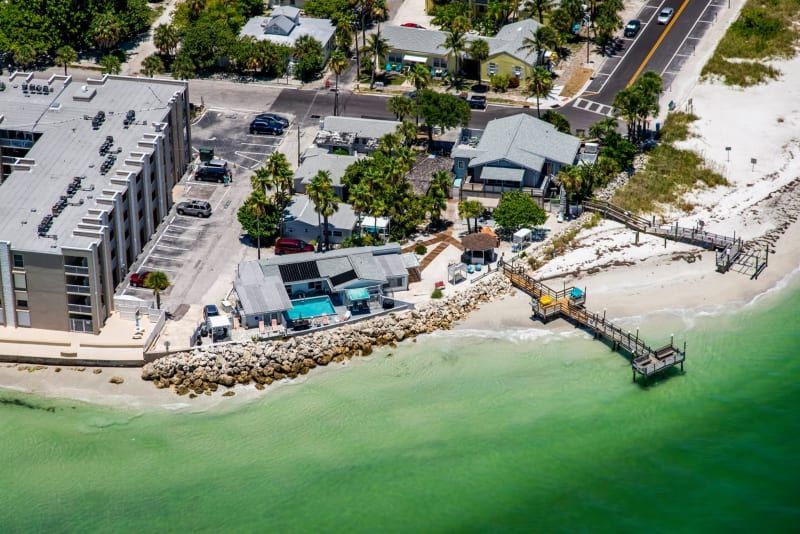 An aerial view of a beach with a dock and buildings