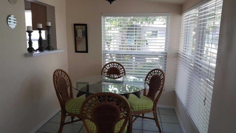 A dining room with wicker chairs and a glass table