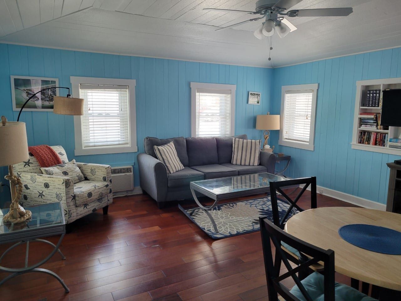 A living room with a couch , chair , table and ceiling fan.