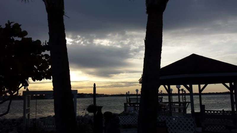 A sunset over a body of water with a gazebo in the foreground