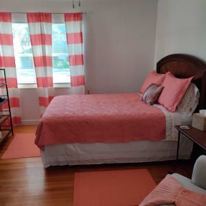 A bedroom with a bed and a window with pink curtains.