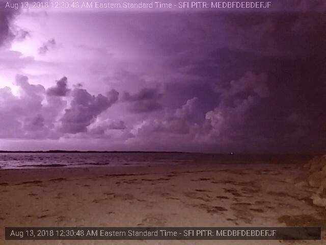 A picture of a beach with purple clouds and lightning