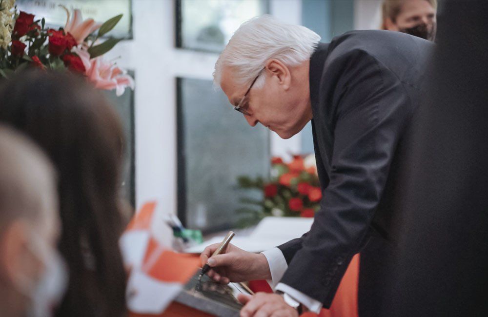 A man in a suit and glasses is signing a piece of paper.