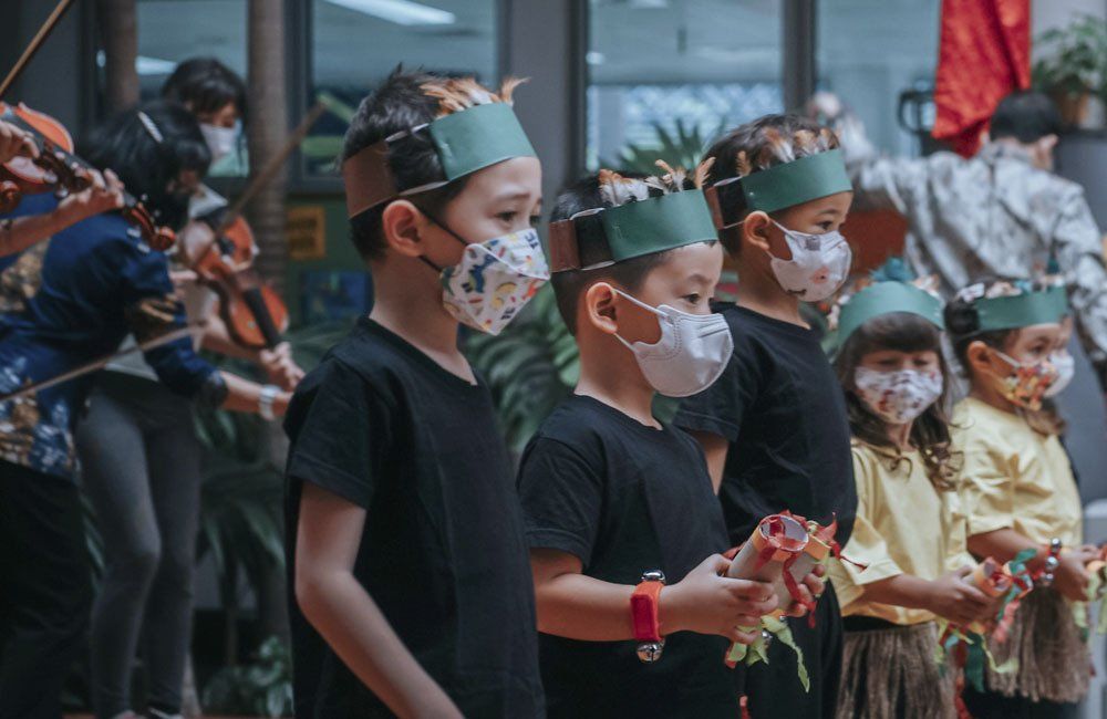 A group of children wearing face masks and crowns are standing in a line.