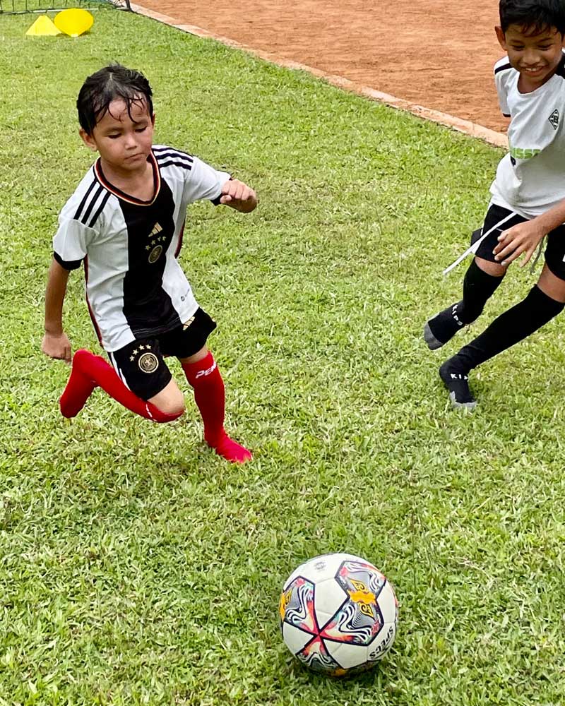 Two young boys are playing soccer on a field.