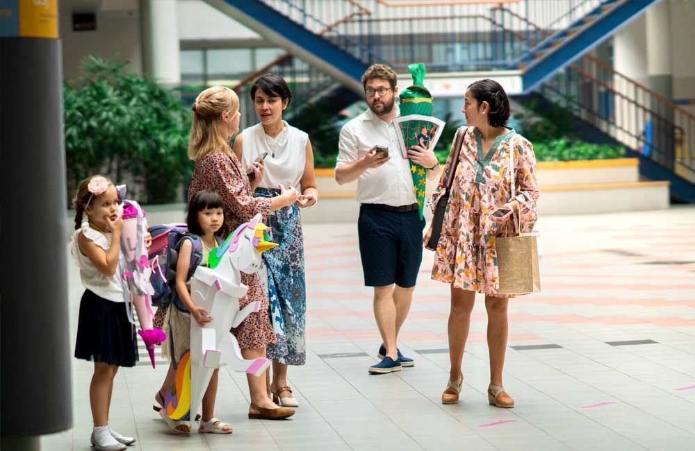 A group of people are standing on a sidewalk talking to each other.