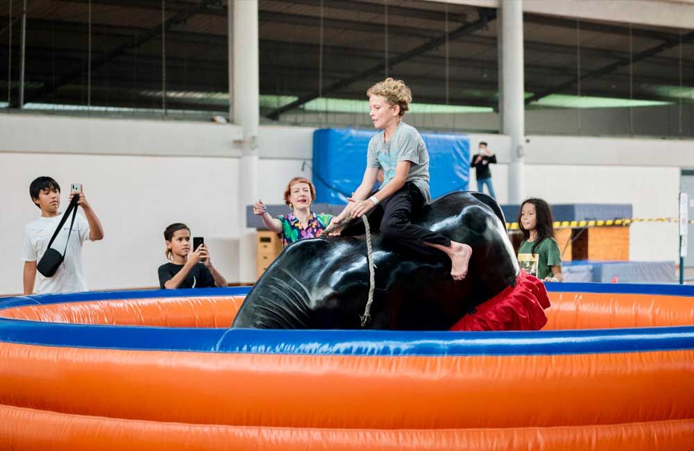 A young boy is riding on the back of an inflatable bull.