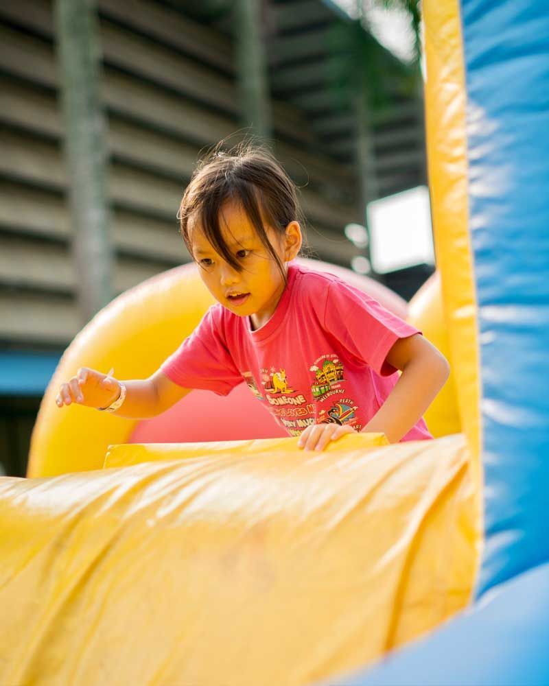 A little girl is playing on a bouncy house.