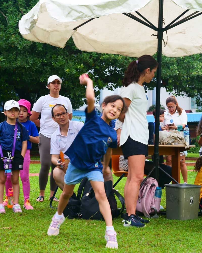 A little girl in a blue shirt is throwing a frisbee