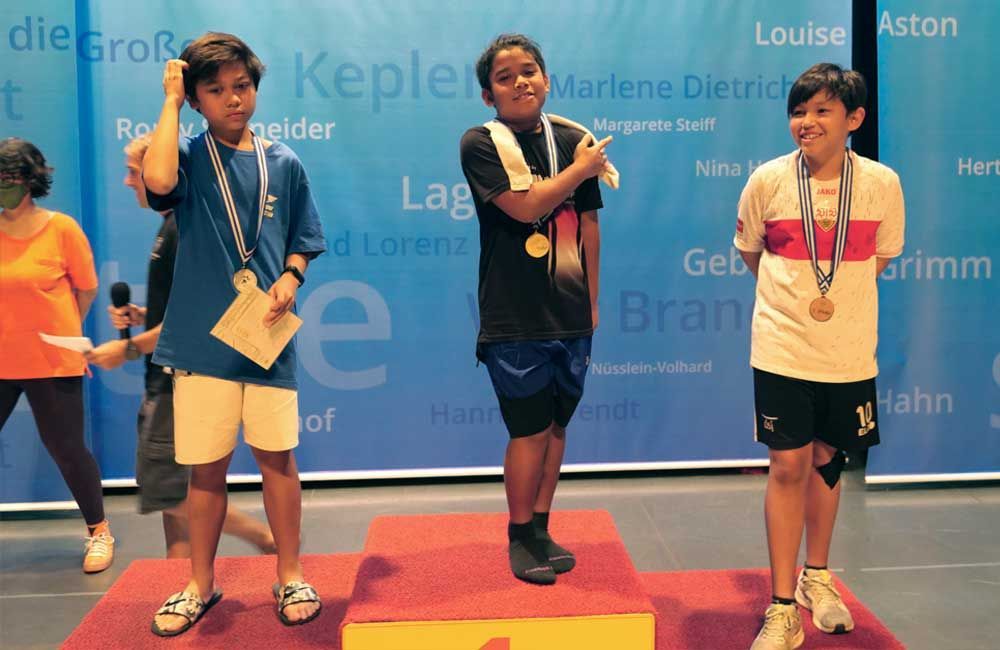 A group of young people standing on a podium with their medals around their necks