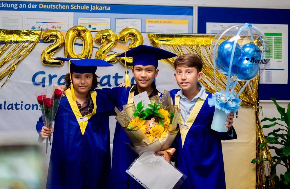 Three boys in graduation caps and gowns are posing for a picture.
