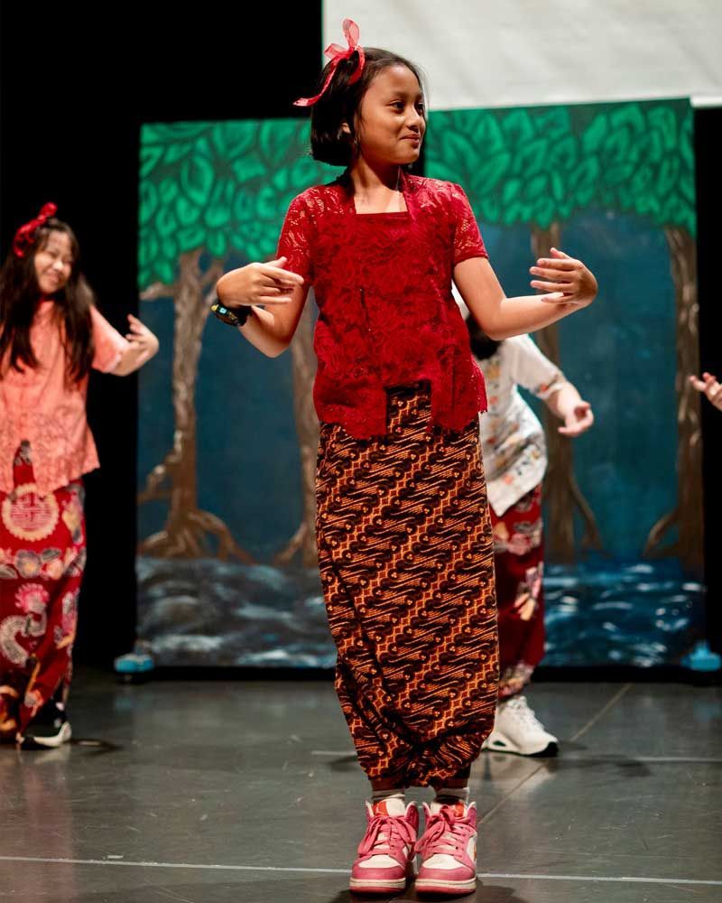 A girl in a red top is dancing on a stage