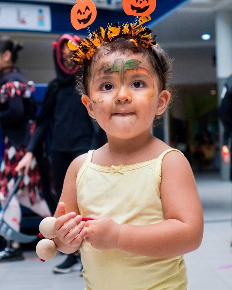 A little girl wearing a headband with pumpkins on it