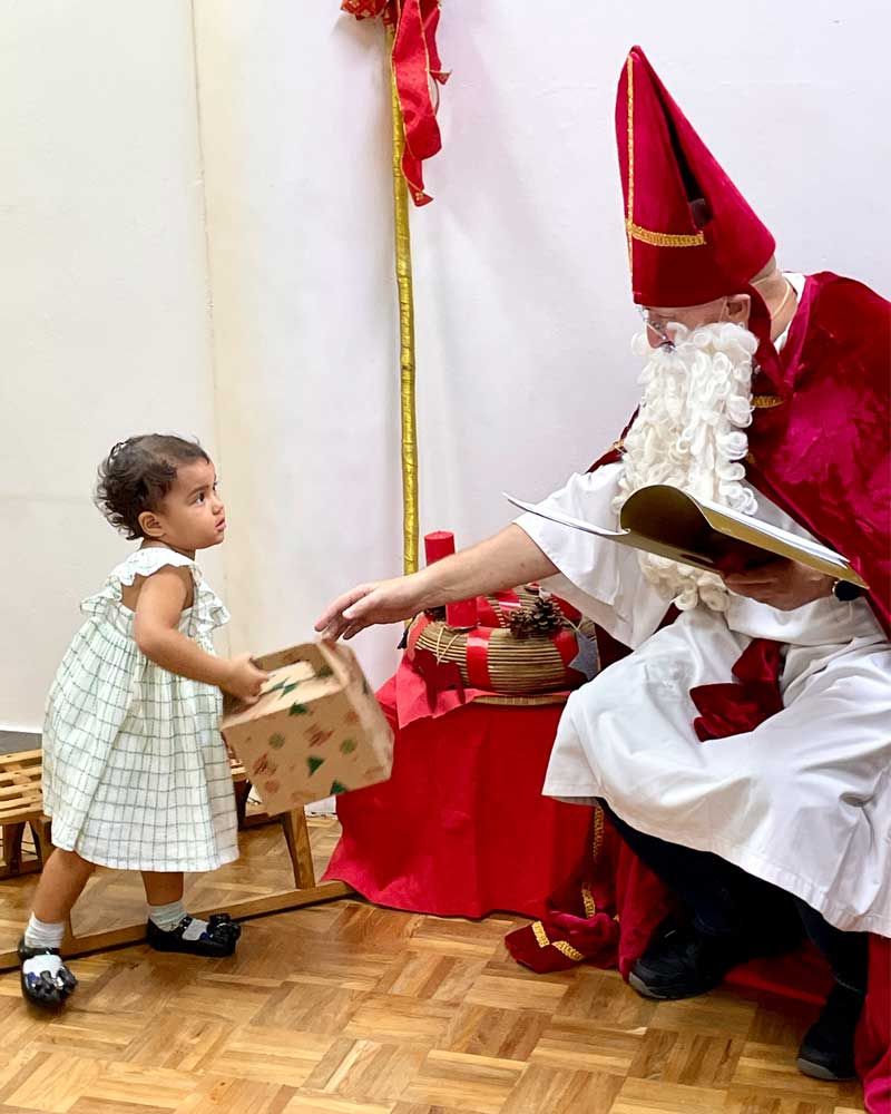 A little girl is standing next to a man dressed as santa claus.