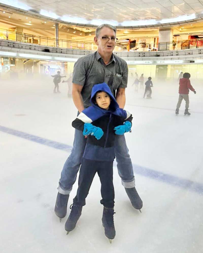 A man and a child are ice skating on a rink.
