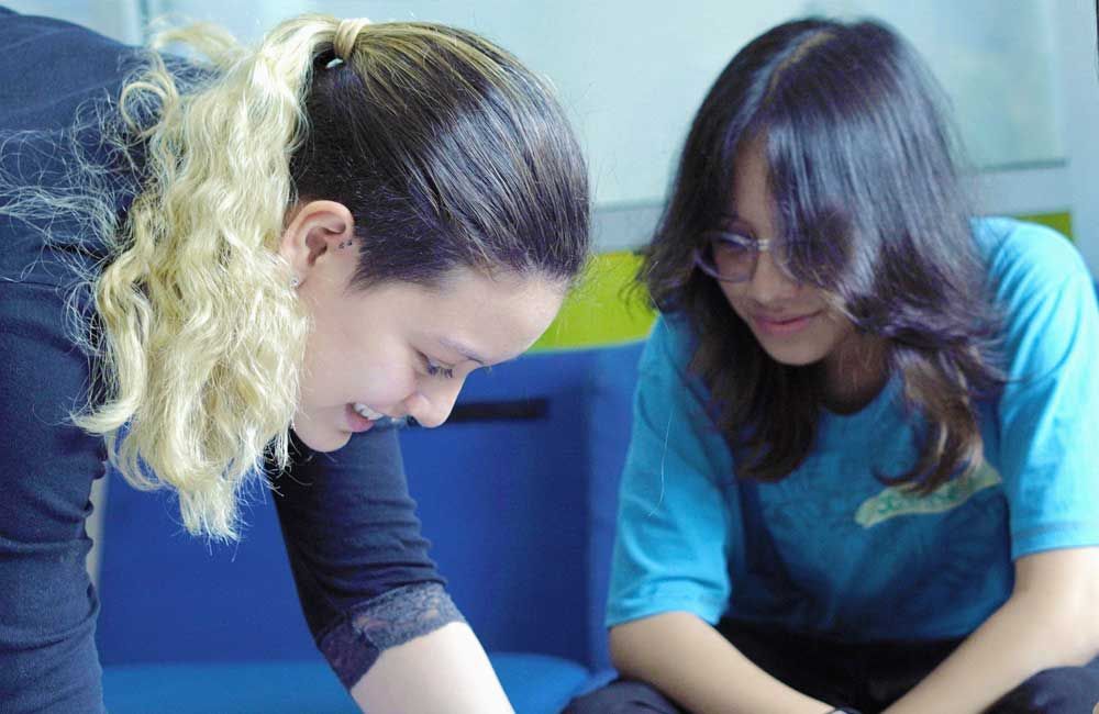 Two women are sitting next to each other on a blue couch.