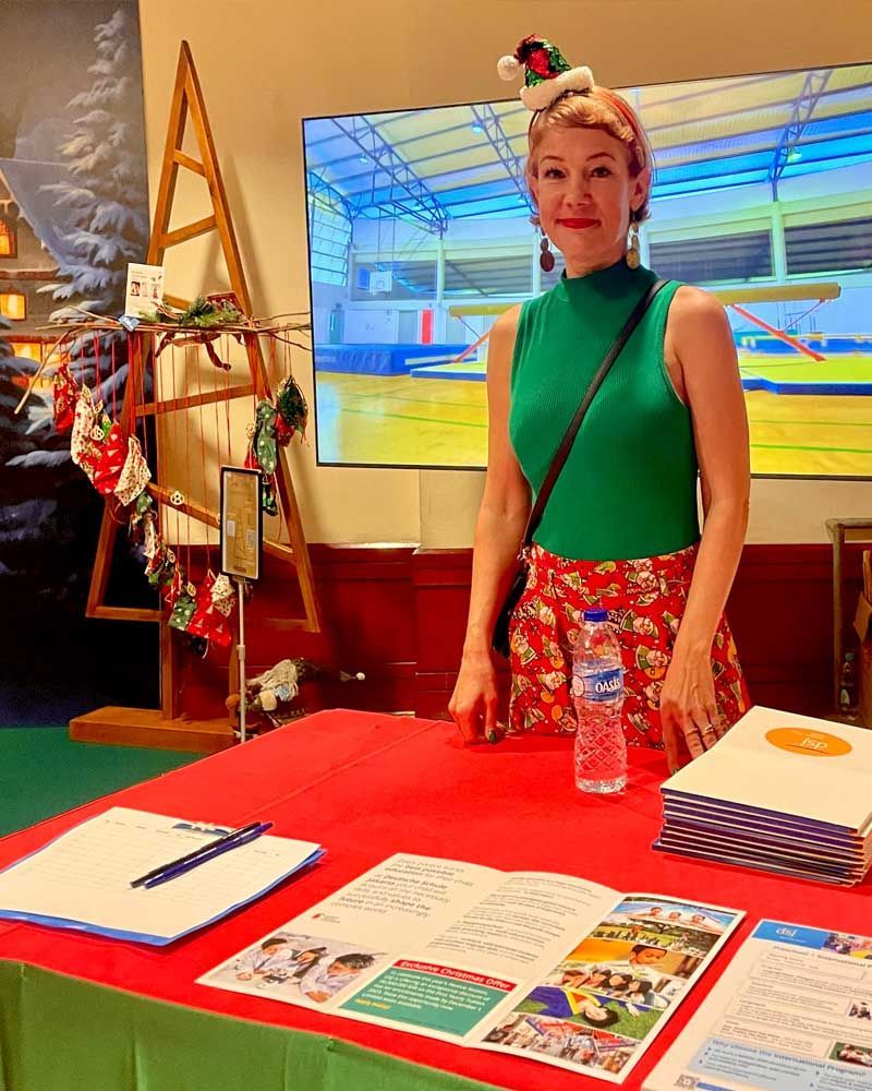 A woman wearing a santa hat is standing at a table.