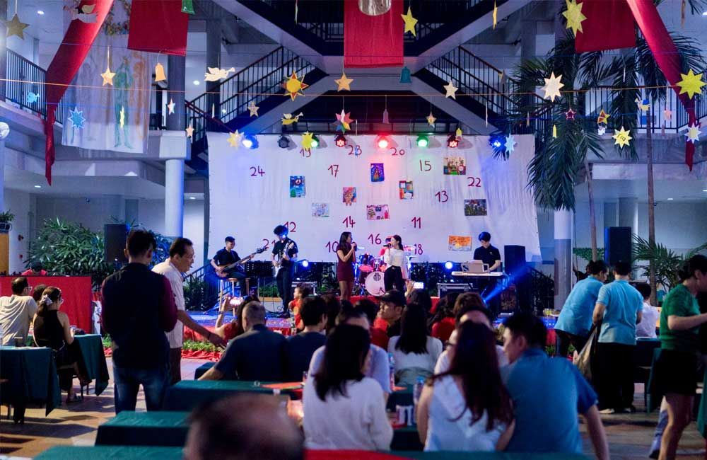 A group of people are sitting at tables in front of a stage at a christmas party.