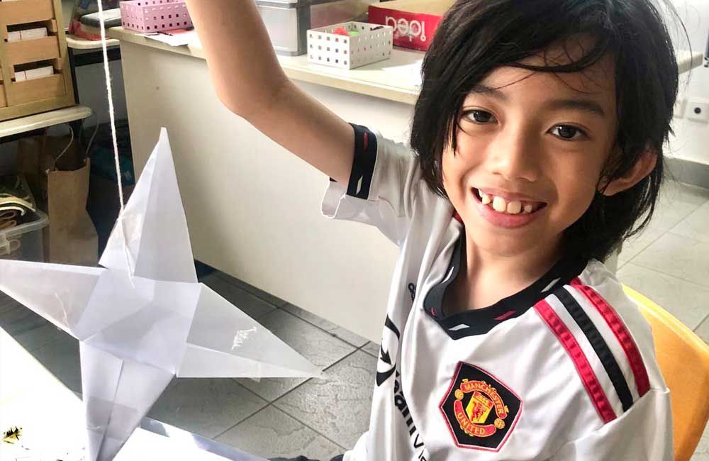 A young boy is sitting at a table holding a paper star.