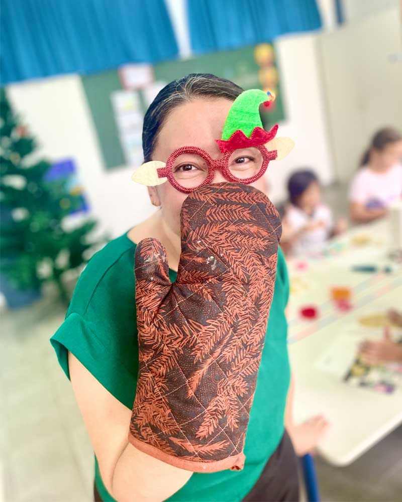 A woman wearing glasses and an oven mitt covering her face