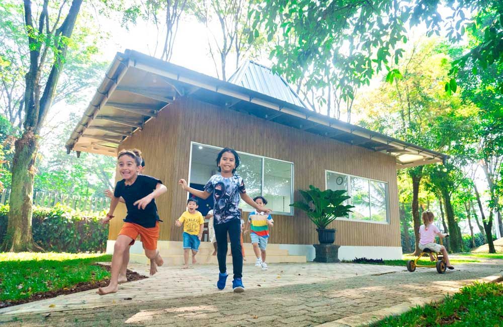 A group of children are running in front of a wooden house.