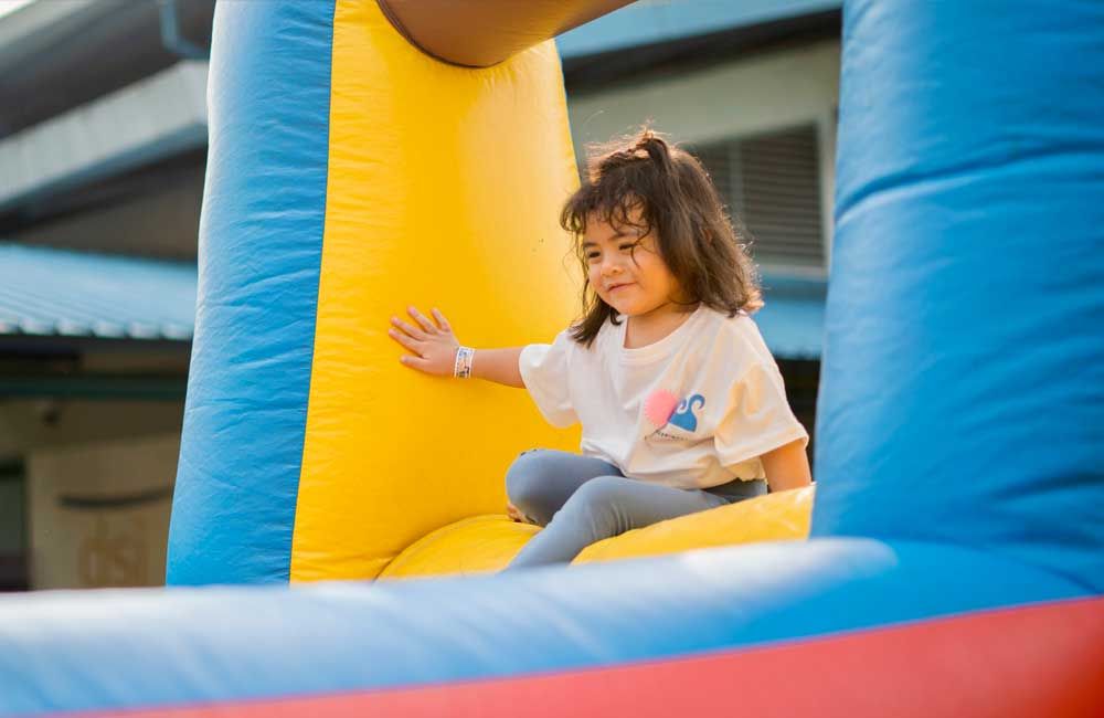 A little girl is sitting on top of a bouncy house.