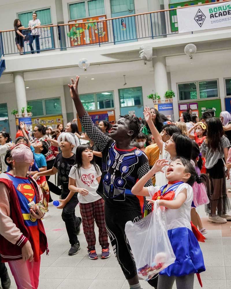 A group of children dressed in costumes are dancing in front of a building.