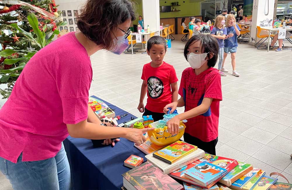 A woman in a pink shirt is serving food to two children.