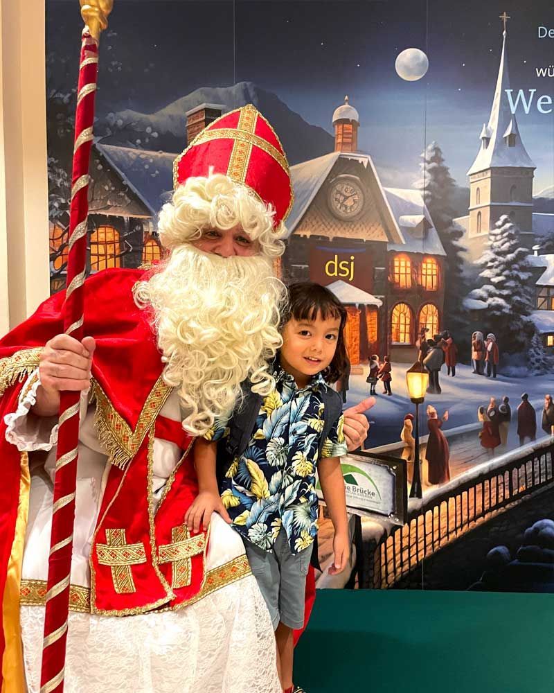 A little boy is standing next to a man dressed as santa claus.