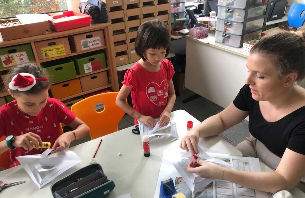 A woman is sitting at a table with two children.