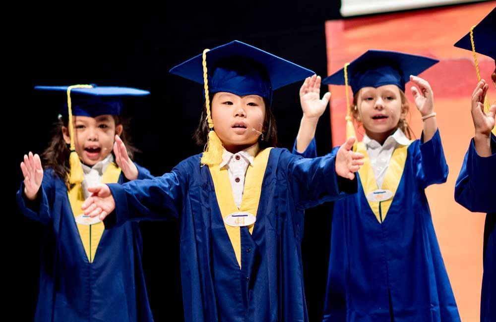 Three children wearing academic robes and hats from DSJ