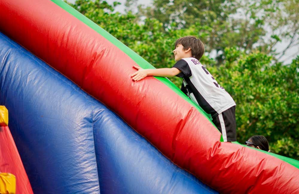 A young boy is climbing up a large inflatable slide.