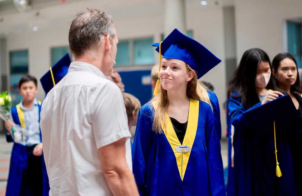 A man is talking to a girl in a graduation cap and gown.