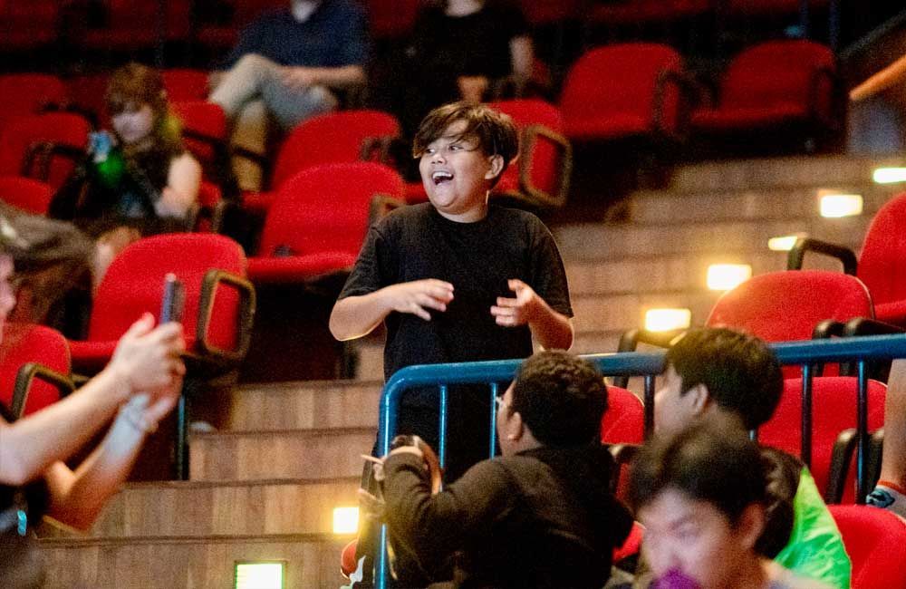 A young boy is standing in the stands of a theater.