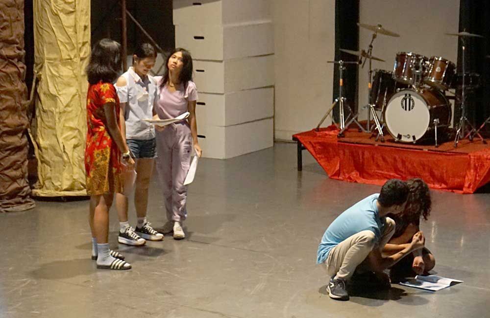 A group of people are standing on a stage in front of a drum set.