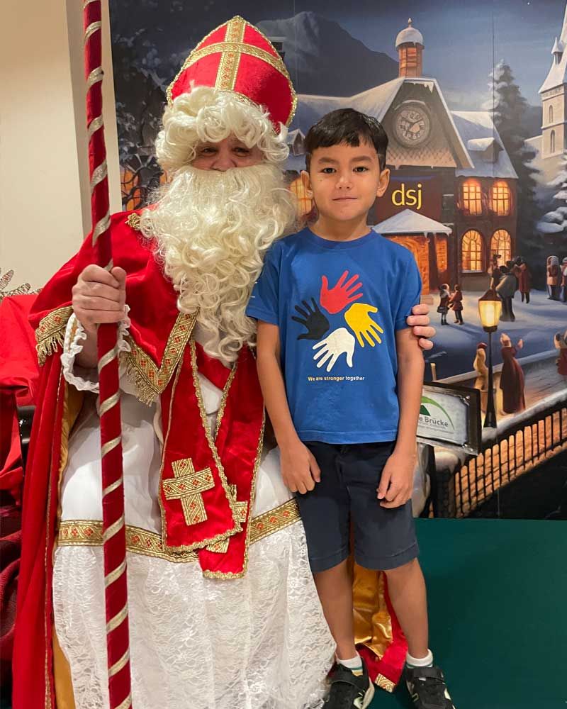 A young boy is posing for a picture with a man dressed as santa claus.