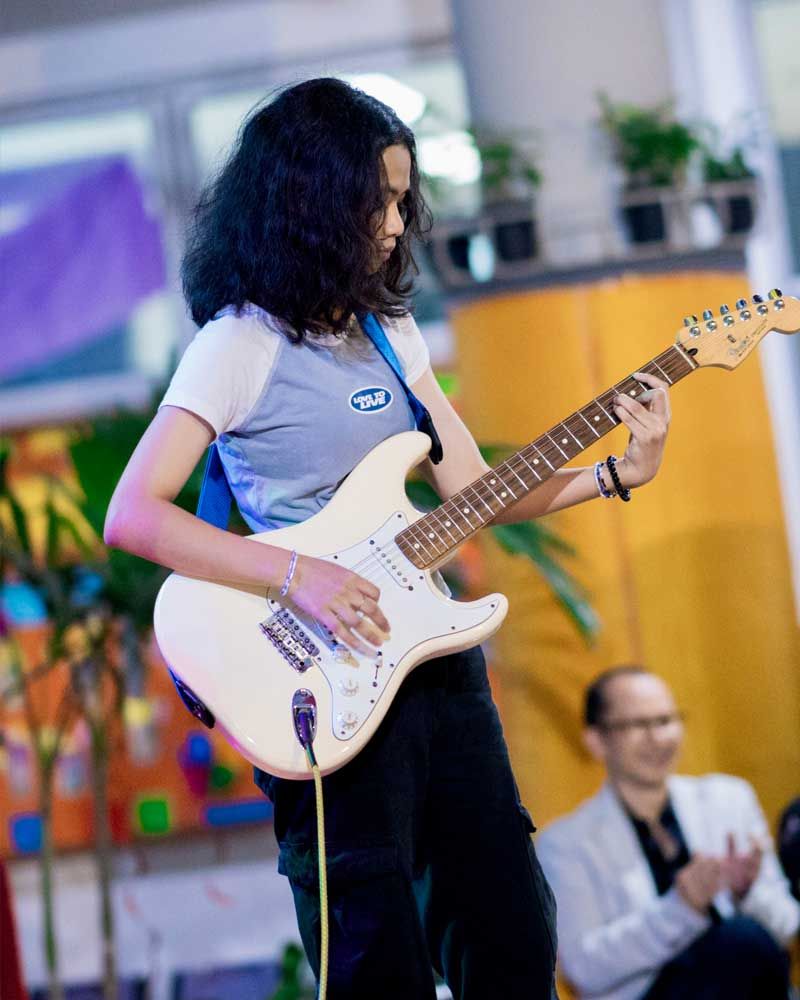 A woman is playing an electric guitar on stage