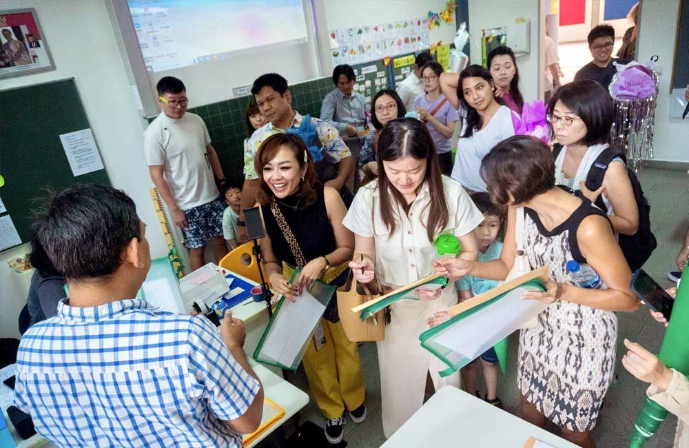 A group of people are standing around a table in a classroom.