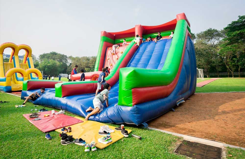 A group of people are playing on an inflatable slide in a park.