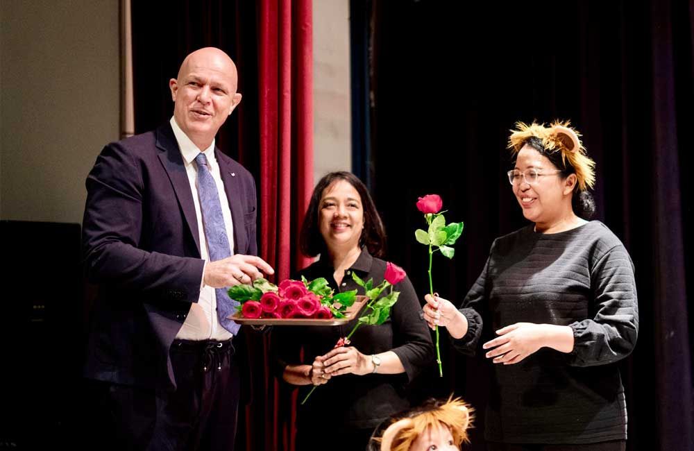 A man in a suit and tie is holding a tray of roses.