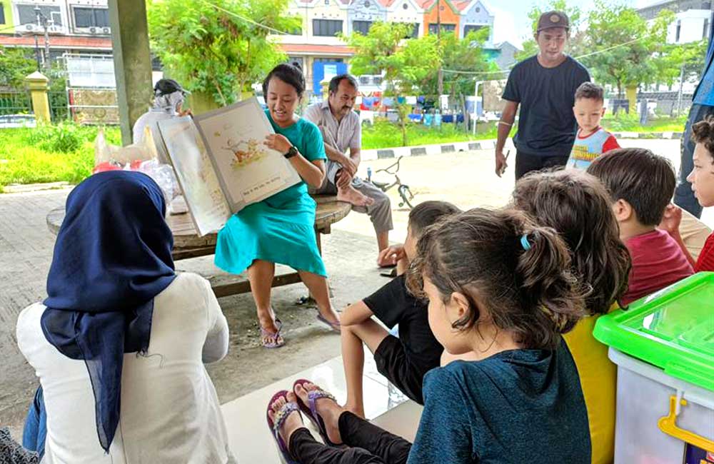 A woman is reading a book to a group of children.