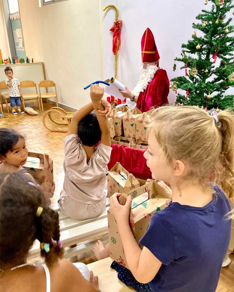 A group of children are sitting in front of a christmas tree.
