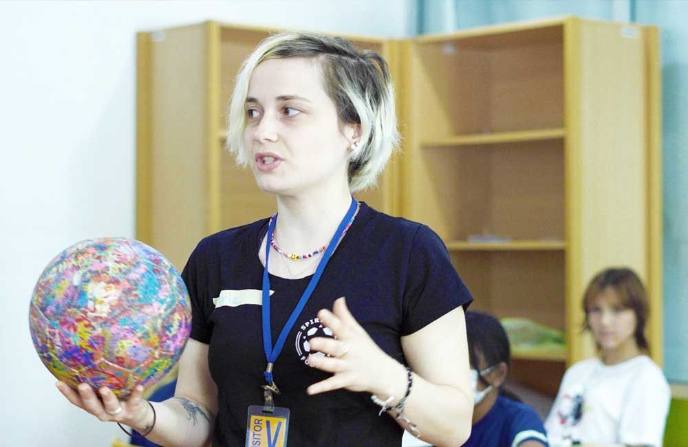 A woman is holding a colorful ball in her hands.