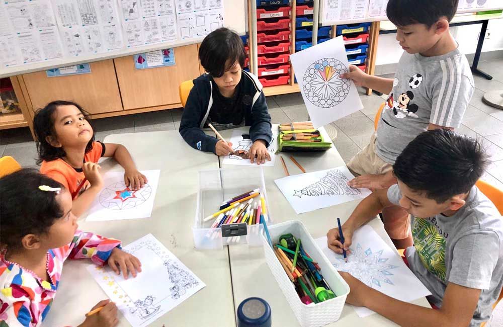 A group of children are sitting around a table drawing.