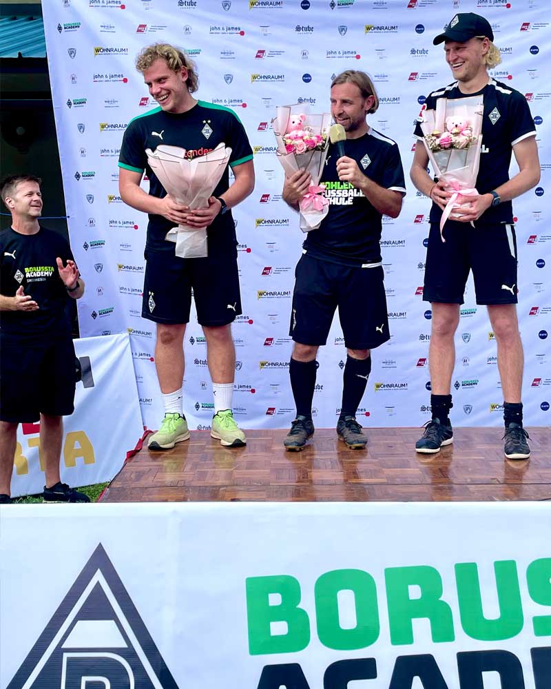 A group of men standing in front of a sign that says borusu academy