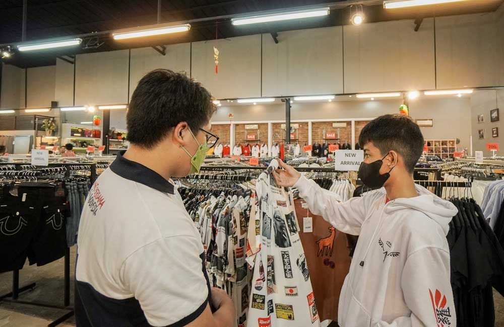 A man and a boy are looking at clothes in a store.