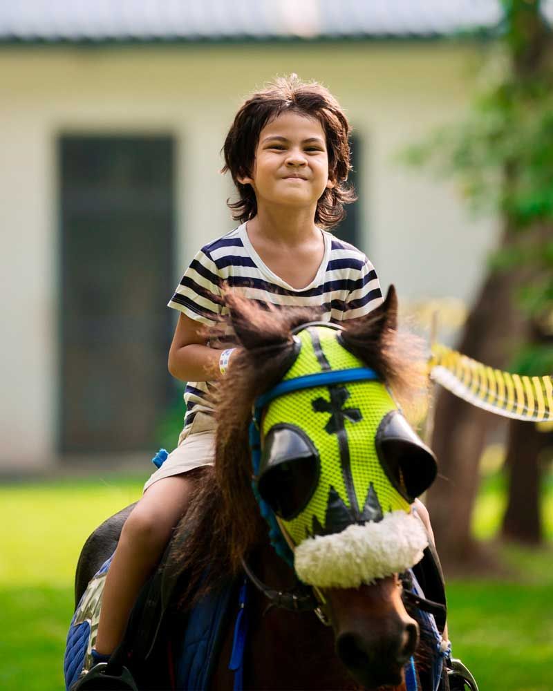 A little girl is riding on the back of a brown horse.