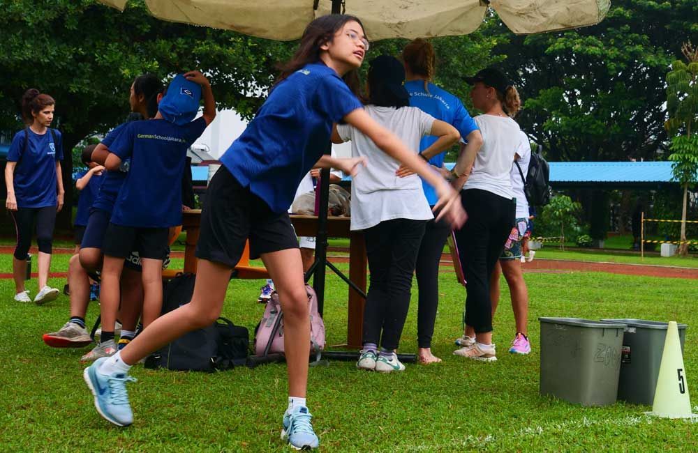 A girl in a blue shirt is throwing a frisbee in a field.